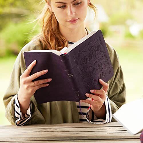 Woman reading a purple leathersoft Bible with decorative text on the cover.