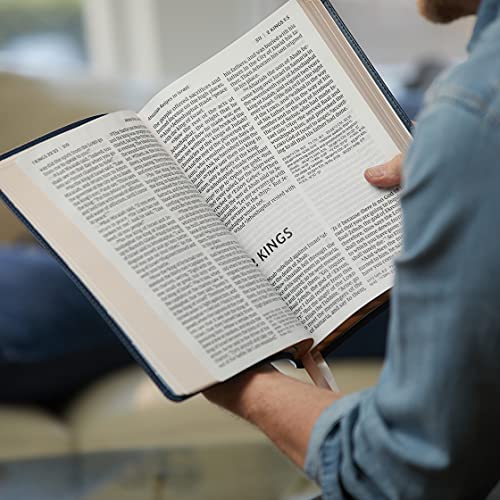Open black Bible with large print and red lettering, being held by a person.