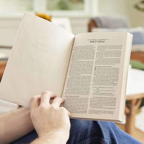 A person holding open a New Testament Bible showing the Gospel of Matthew.