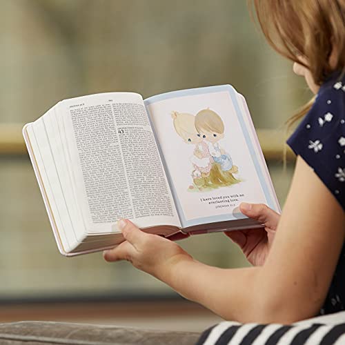 A child holds an open Precious Moments Bible featuring a colorful illustration of two children.