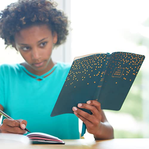Young woman reading an open blue leathersoft Bible, taking notes.