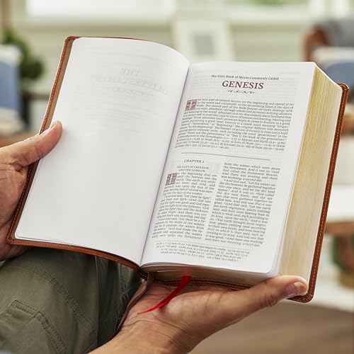 Open black leather-look Bible displaying the Book of Genesis, held in hands.