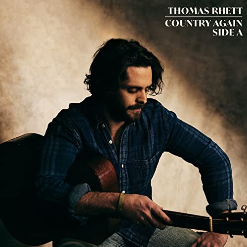 Thomas Rhett playing an acoustic guitar against a textured beige background.
