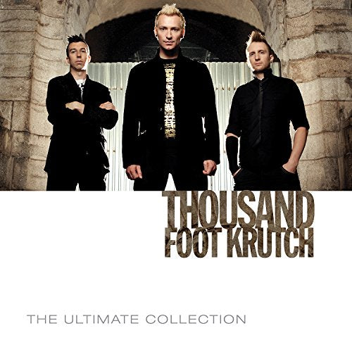Three men in black stand before a stone archway, album cover.