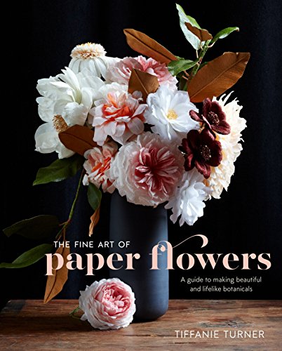 A bouquet of paper flowers in a dark vase on a wooden table.