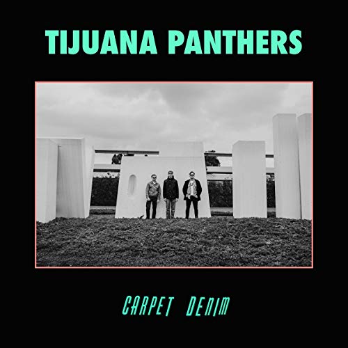 "Black-and-white album cover with three men standing in front of abstract white structures."