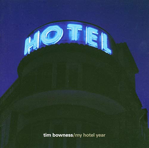 A glowing blue neon hotel sign atop a dark building at night.