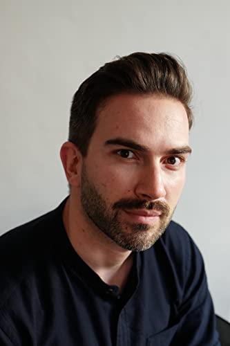 Close-up portrait of a young man with dark hair and a beard.
