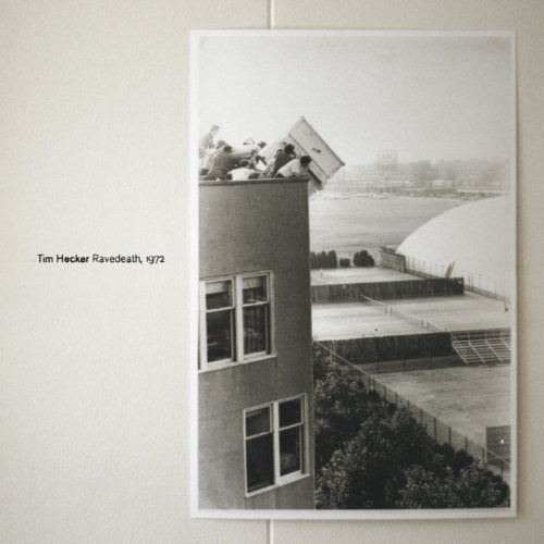 Black and white album cover with a building and people on the roof.