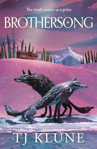 Two wolves stand on a snowy landscape before a cabin and mountain range.
