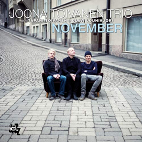 CD cover with three men seated on a vintage sofa in front of buildings.