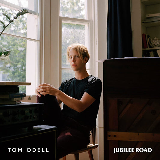 "Tom Odell sitting by a window with a piano, album cover art."