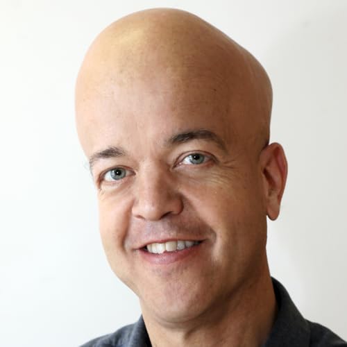 Close-up of a smiling, bald man with light eyes against a white background.
