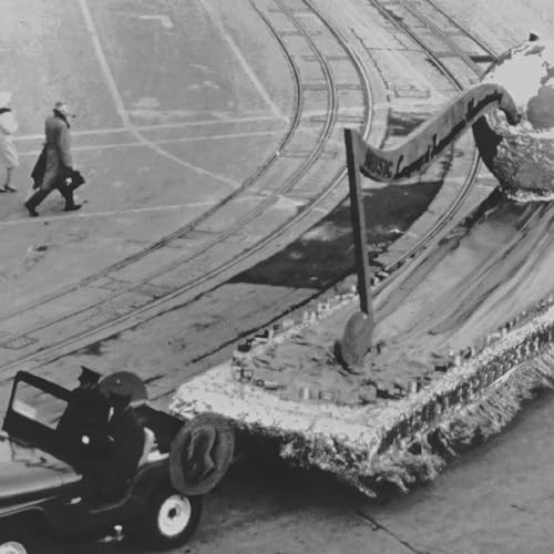 Black and white photo of a parade float and people walking nearby.