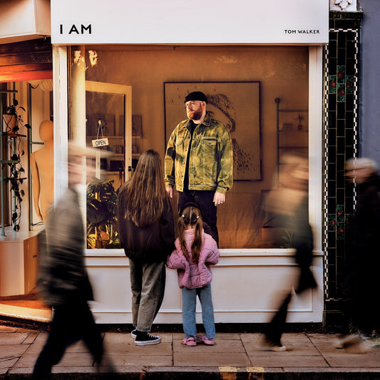 CD cover featuring a man in a yellow jacket standing in a storefront.