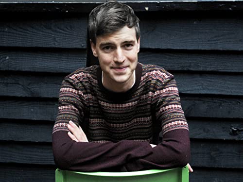 Young man with short dark hair wearing a patterned sweater.