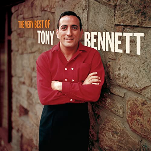 Tony Bennett in a red shirt standing against a stone wall on album cover.