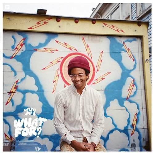 A smiling man in a maroon beanie stands before a mural of lightning bolts.