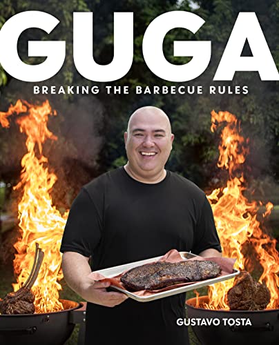 A smiling man holds a tray of cooked meat in front of large flames.