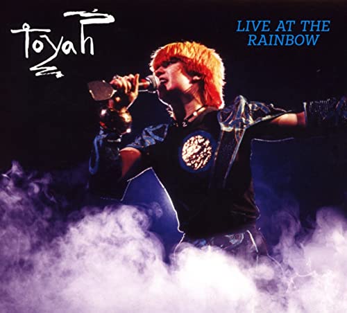 Toyah Wilcox singing into a microphone onstage with smoke effects.