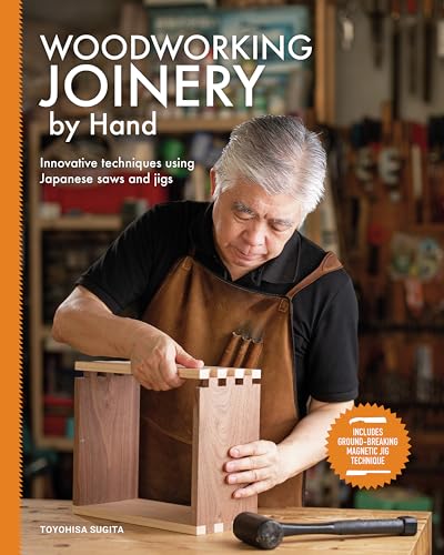 A man in a leather apron assembles a wooden box in a workshop.