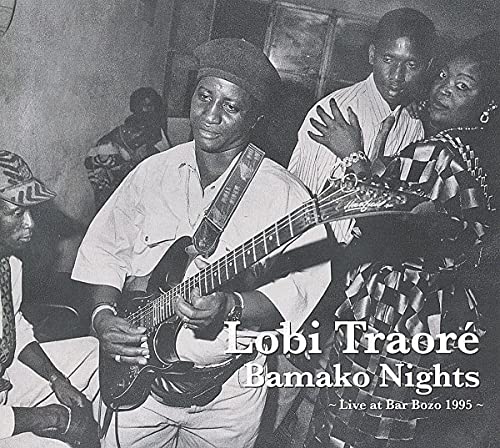 Black and white photo of Lobi Traoré playing guitar with band members.