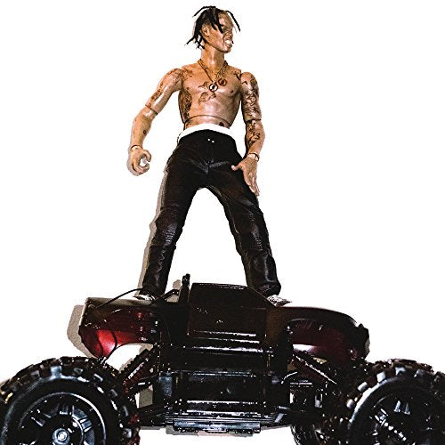 Travis Scott action figure standing on a black toy monster truck against white background.