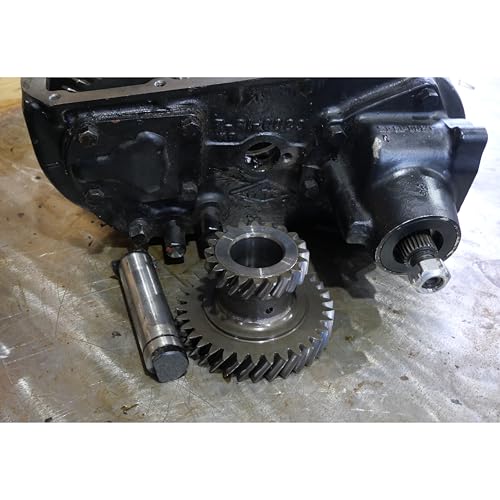 Disassembled Jeep transfer case with gears and a cylindrical shaft.