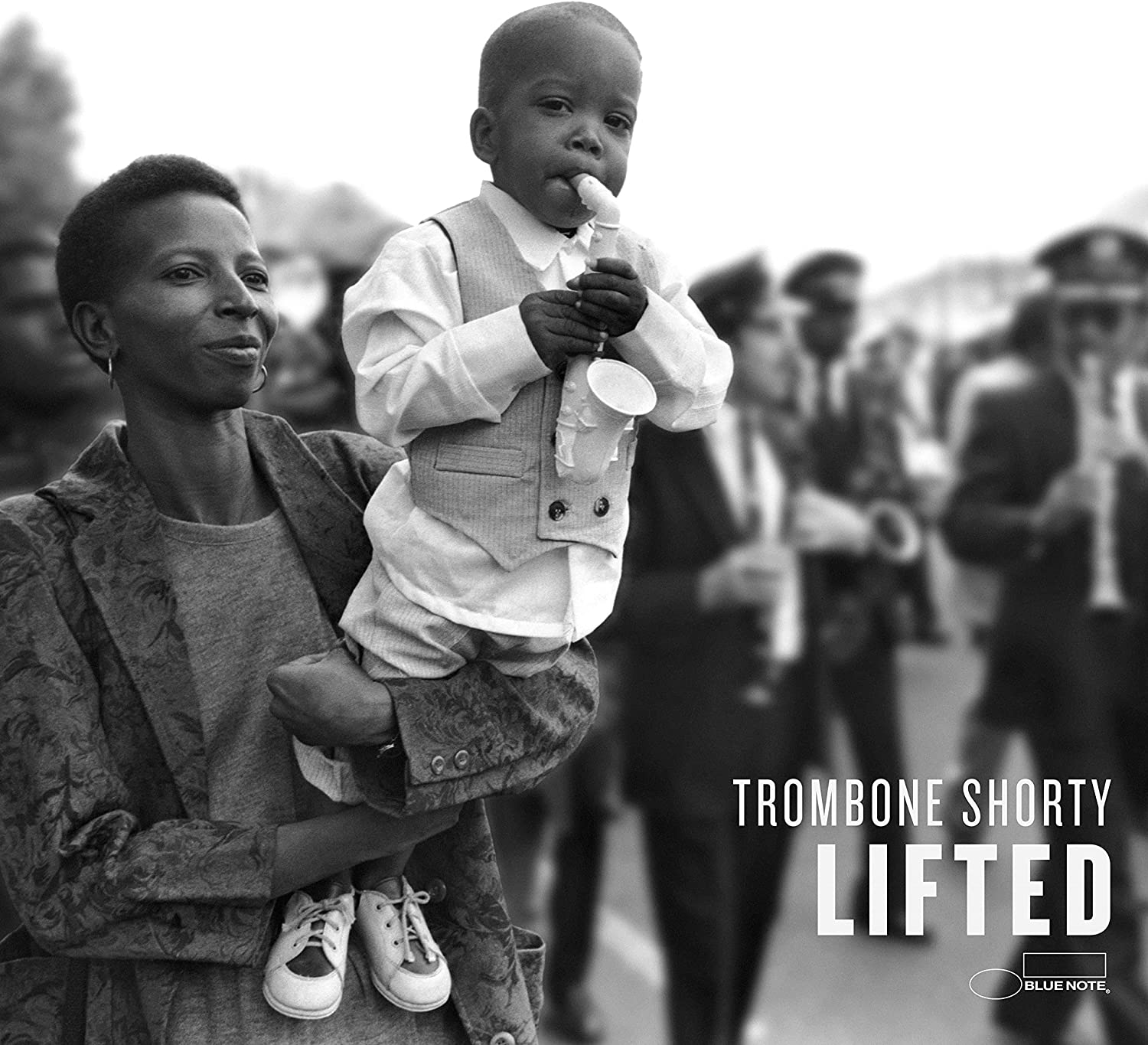 Black and white photo of young Trombone Shorty being carried by a woman.