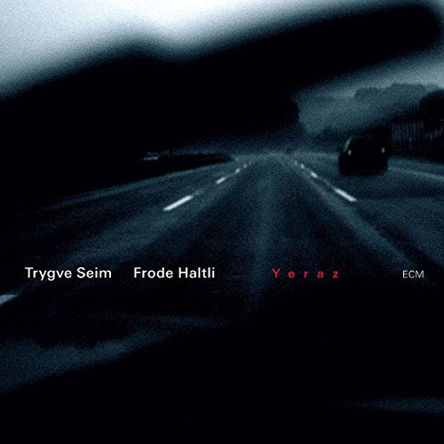 "Album cover with dark, blurry road scene and artist names in white and red text."