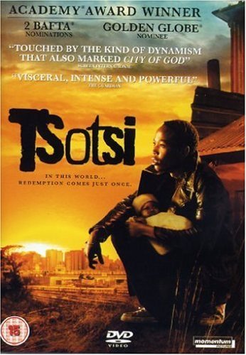 A man in a leather jacket holds a baby against a sunset city background.