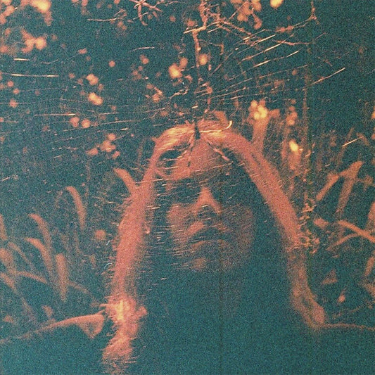 Blurred, grainy image of a person’s face against a dark, textured background.