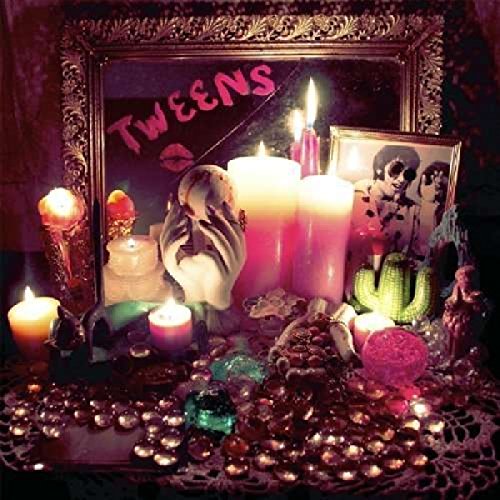 A mirror reflecting the word Tweens and a table covered in candles and crystals.