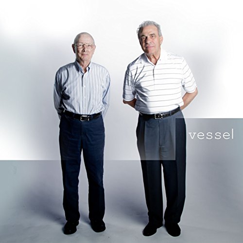 Two older men standing against a white background with the word vessel printed.