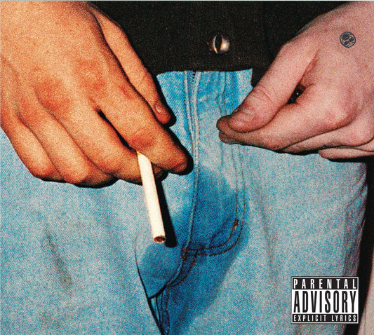 Hands holding a lit cigarette over blue pants, parental advisory label.