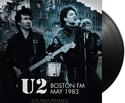 Black and white photo of U2 performing live with a vinyl record beside it.