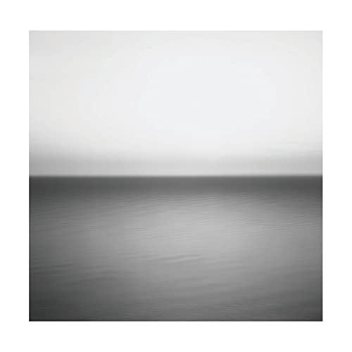 Minimalist black and white photograph of a calm sea meeting a bright, hazy sky.