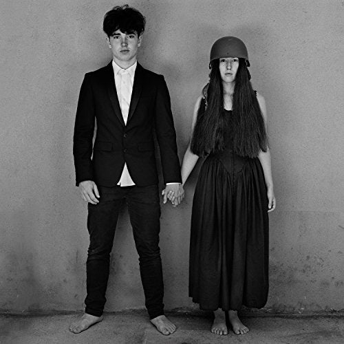 Black and white photo of a couple holding hands, she wears a helmet.