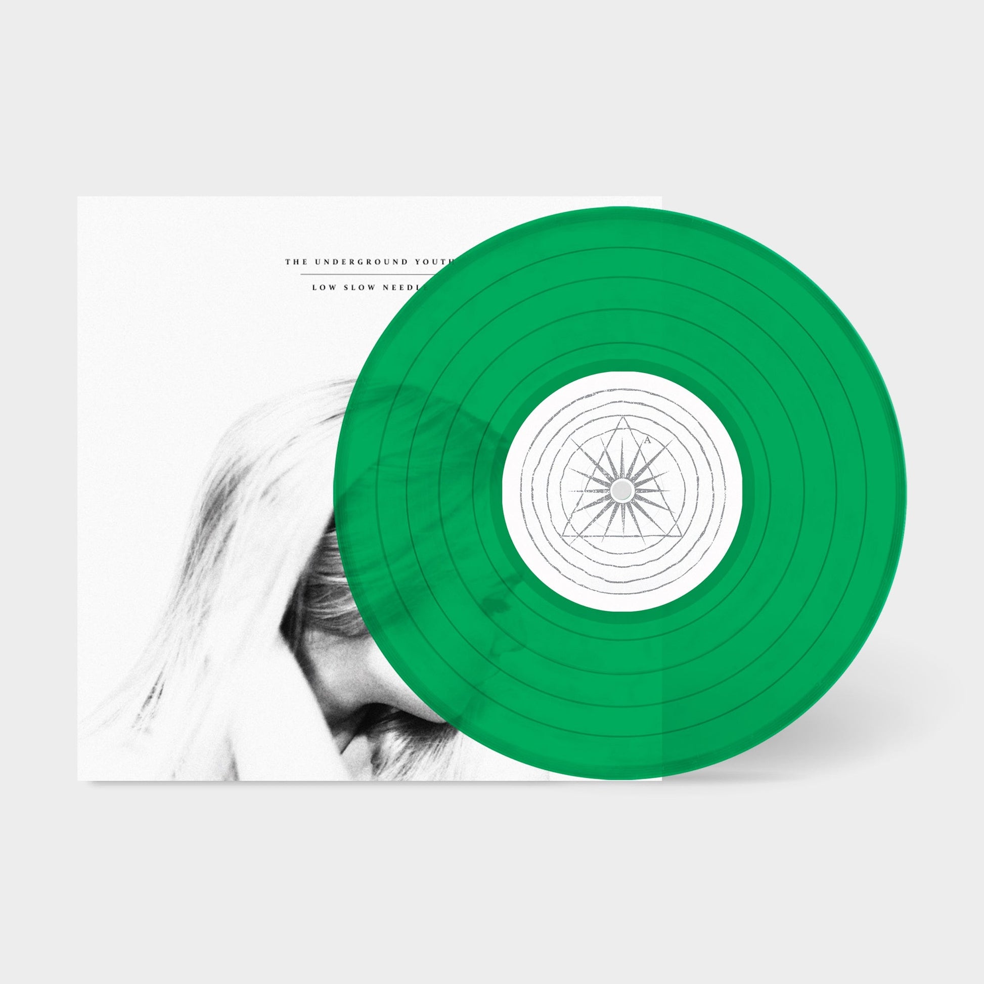 Green vinyl record with white label and partial album cover visible.