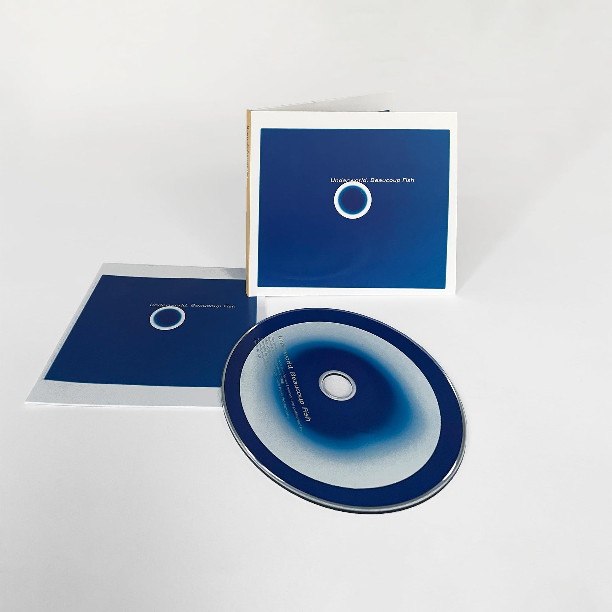 Underworld’s “Beaucoup Fish” CD in a clear plastic sleeve, blue cover.