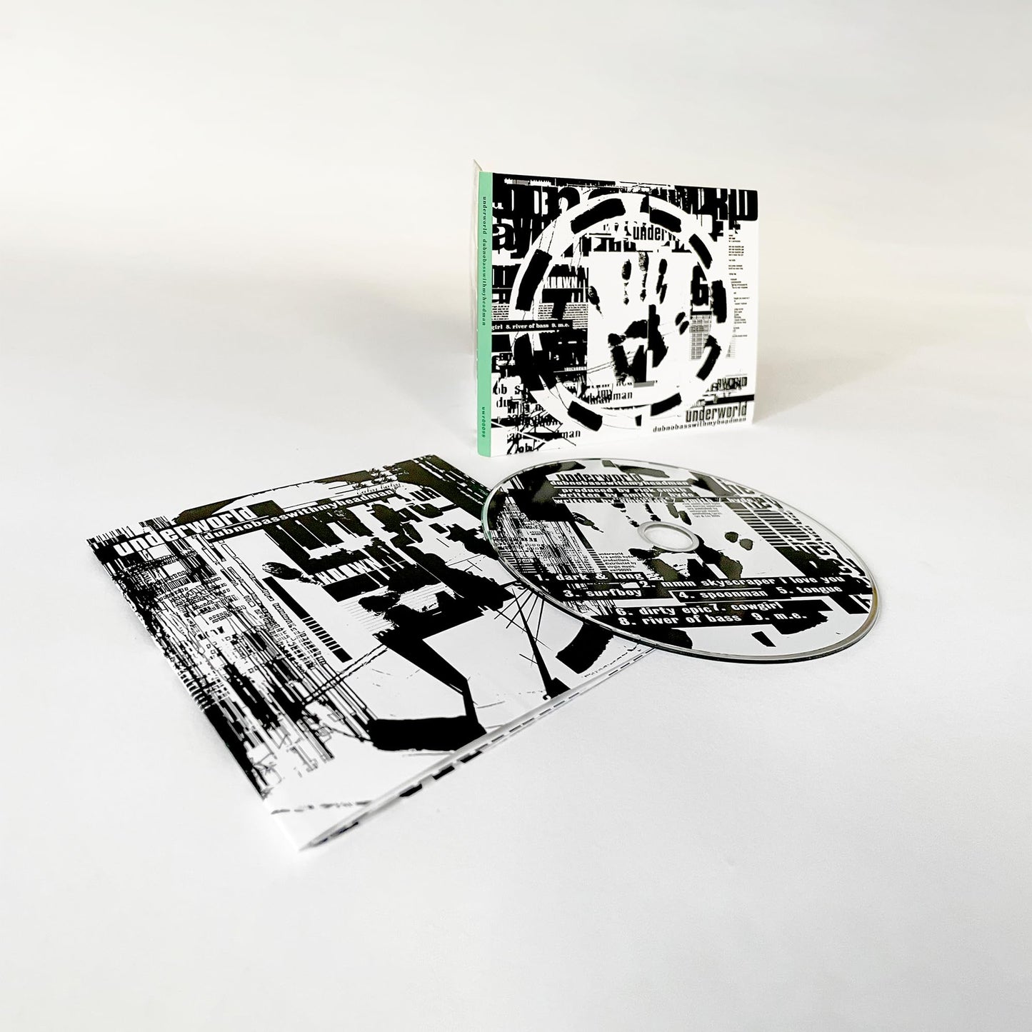 Underworld’s “Dubnobasswithmyheadman” CD case open with disc, black and white abstract design.
