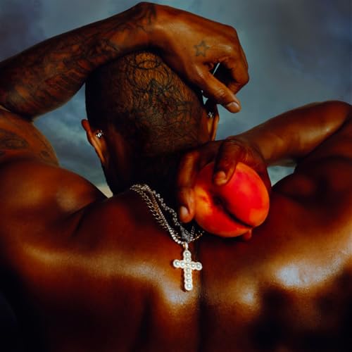 A shirtless man with tattoos holding a peach against his back with a cross necklace.