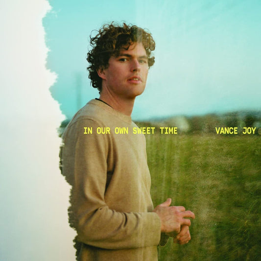Vance Joy album cover featuring a man in a beige sweater standing outdoors.