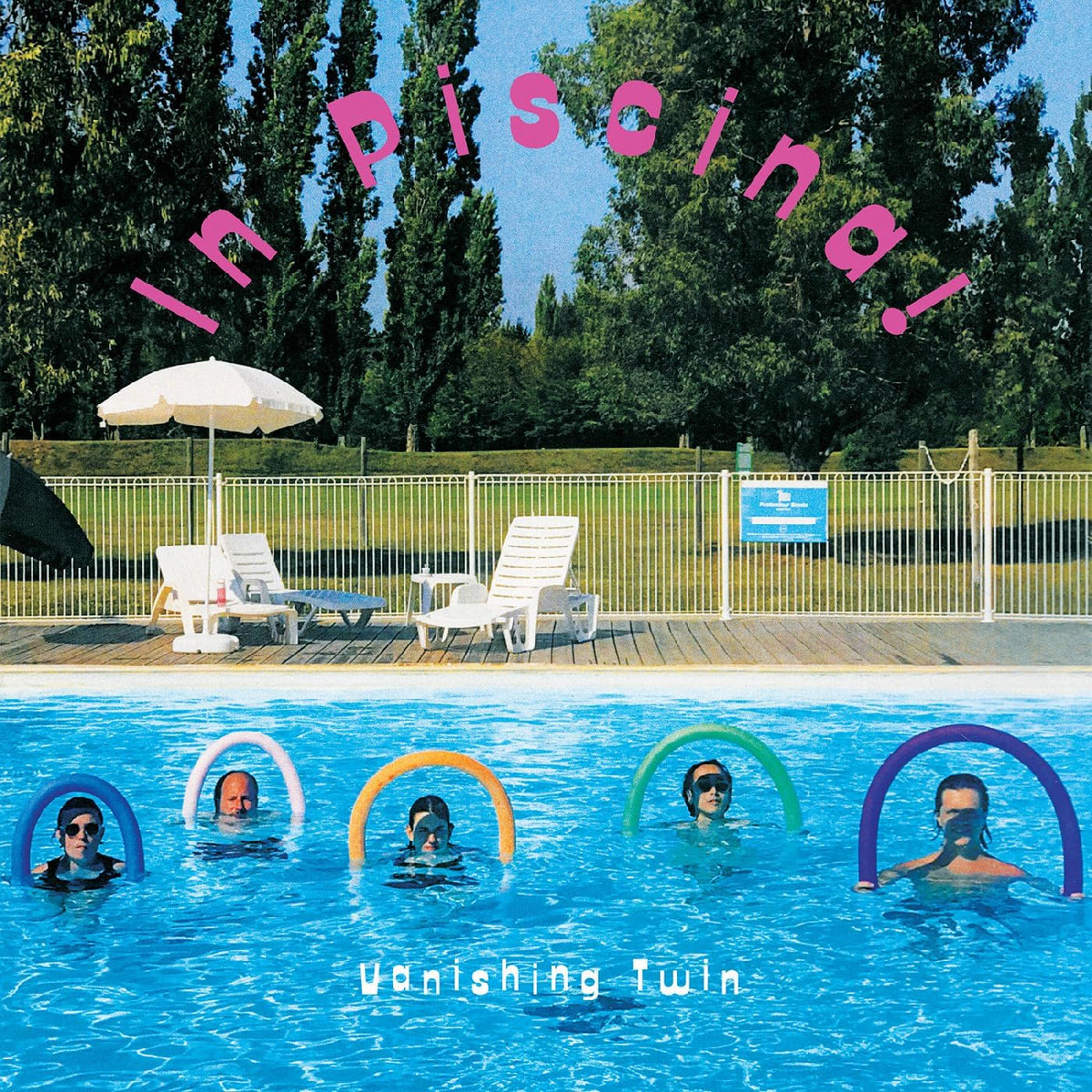 People in a blue swimming pool with colorful inflatable rings.