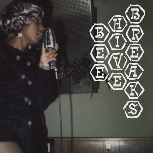 A woman with a beehive hairstyle sings into a vintage microphone.
