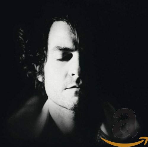 Black and white portrait of a man, partially in shadow, with an Amazon logo.