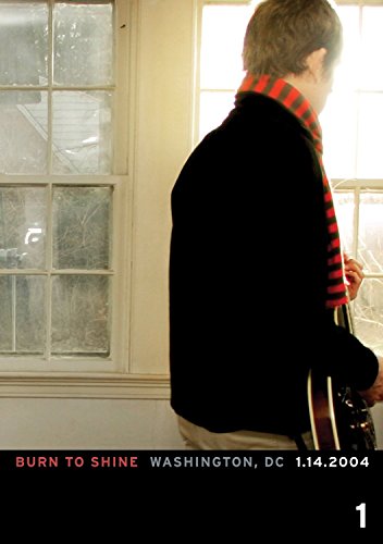 "Man holding a guitar stands in front of a window, DVD cover art."