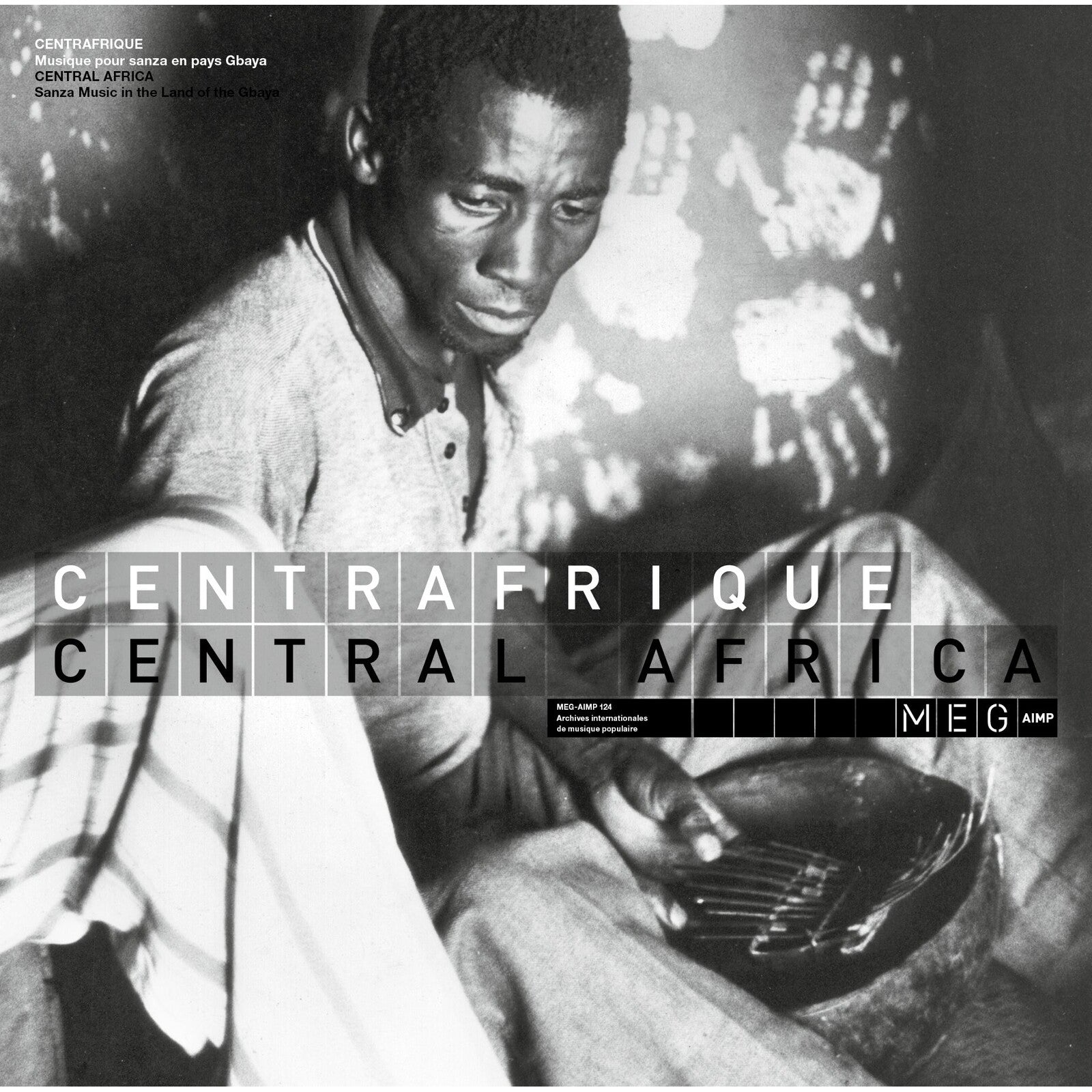Black and white photo of a man playing a sanza instrument in Central Africa.