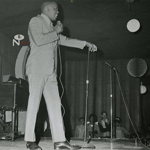 Black and white photo of a singer performing with a band onstage.