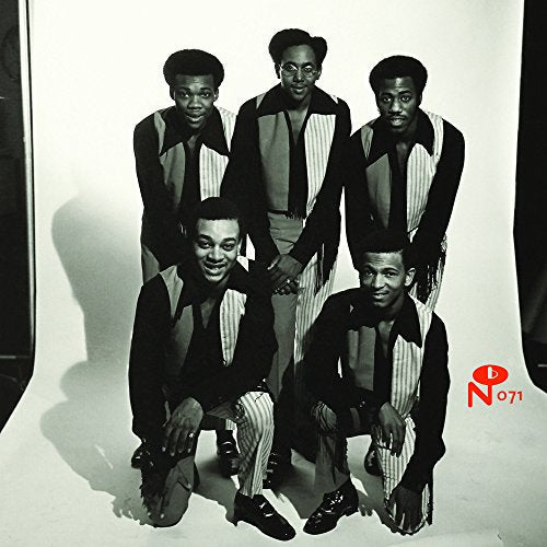 Black and white studio portrait of five men in matching outfits posing together.